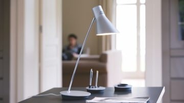 Una luminaria de mesa sobre un escritorio apuntando al papel y al bolígrafo
